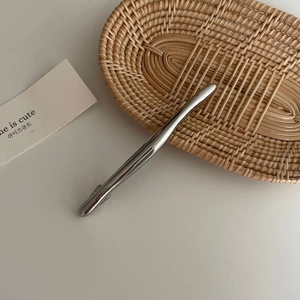 Minimalistische lange Haarklammer aus Silber auf einem rustikalen geflochtenen Tablett