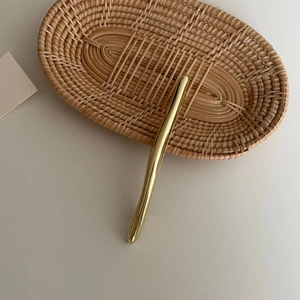 Nahaufnahme einer minimalistischen goldenen Haarspange mit flüssiger Kurvenoberfläche