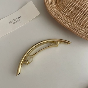 Nahaufnahme einer minimalistischen goldenen Haarspange aus Metall mit Hochglanz-Finish
