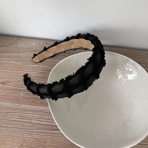 Close-up of black fringe texture headband on white ceramic bowl over wood table