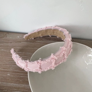 Pink plush textured sponge headband with grid pattern displayed on a white ceramic bowl