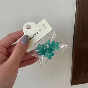 Détail de pinces à cheveux à fleurs vertes dans un emballage avec carte de suspension