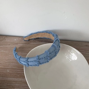 Close-up of blue denim braided headband with vintage fringed edges and soft lining