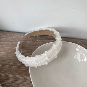 Detailed view of white quilted textured headband with soft fuzzy fabric on wooden surface