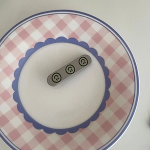 Barrette à cheveux grise minimaliste avec smileys verts sur assiette décorative