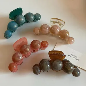 Détail de pinces à cheveux marbrées en dégradé de vert, rose, pêche et gris