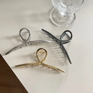 Trois grandes pinces à cheveux de 14 cm en métal or, argent et gris anthracite sur bureau