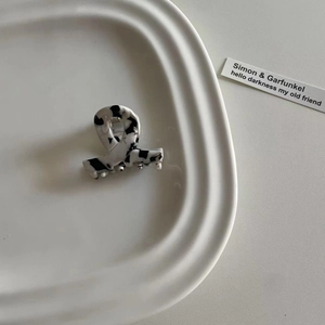 Minimalistische Haarklammer aus Acetat mit Marmormuster auf einem weißen Tablett