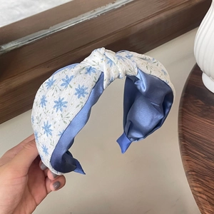 Détail du motif floral et de la texture en satin bleu sur le bandeau noué