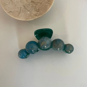 Détail d'une grande pince à cheveux avec perles marbrées et base à dents larges vertes