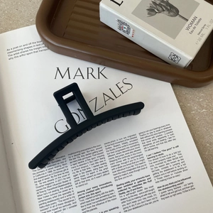 Minimalist matte black rectangular acrylic hair claw clip on a stylish magazine