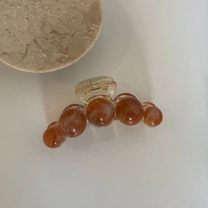 Gros plan sur une pince à cheveux élégante avec perles ambrées et ressort en acrylique