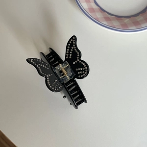 Vue détaillée de la pince à cheveux papillon noire ornée de strass brillants sur blanc