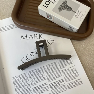 Deep brown matte acrylic hair claw clip for bun styles displayed on a fashion magazine