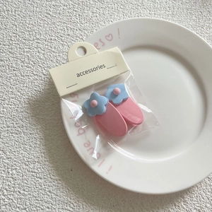 Detail of two pink and blue floral hair clips on white ceramic plate with card