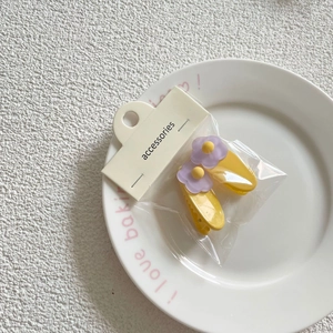 Detail view of two sweet yellow floral hair clips in elegant retail packaging on a tray