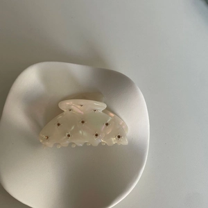 Pince à cheveux élégante en acétate blanc perlé avec strass dans un plat en céramique