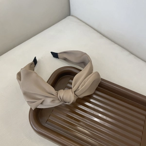 Detail of French style knot headband in beige matte silk fabric on a dark tray