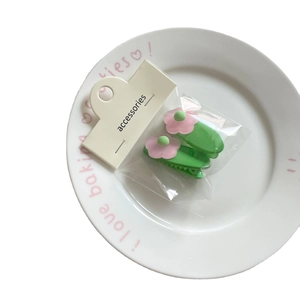 Set of 2 sweet floral duckbill hair clips in green and pink on a white ceramic plate
