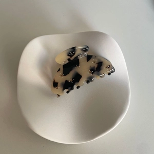 Détail macro d'une pince à cheveux en acétate écaille avec strass sur plateau blanc