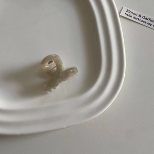 Detail einer perlmuttfarbenen kleinen Haarklammer mit Kreuzdesign auf weißem Tablett