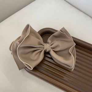 Close-up of a large light coffee bow hair clip with double-layer pleated edges and fine stitching