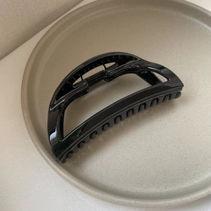 Detailed view of a sleek black large shark hair claw clip with a glossy finish and strong teeth