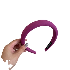 Handheld view of a thick purple sponge headband with Morandi style knitted fabric