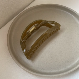 Detailed close-up of dark olive green minimalist shark hair clip on a ceramic plate