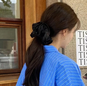 Elegant oversized black satin scrunchie with layered ruffle trim on a ponytail