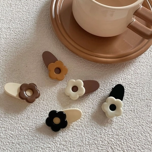 Five-piece set of cream and coffee floral hair clips on a clean white textured background