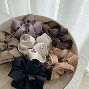 Close-up of assorted satin oversized scrunchies in neutral tones on a display tray