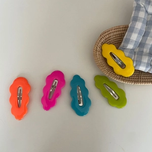 Detailed view of colorful wavy hair clips in five bright shades on a rustic background