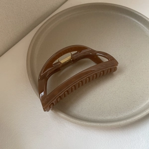 Minimalist large dark brown hair claw clip in a stylish Morandi color ceramic tray