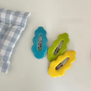 Close-up of three colorful wave-shaped BB hair clips in blue, green and yellow