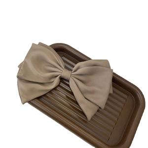 French style large matte beige satin bow hair clip on a minimalist display tray