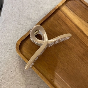 Close-up of a large nude and transparent crossover claw clip on a wooden tray