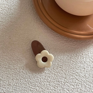 Detailed macro view of the flower hair clip showing smooth resin texture and warm tones