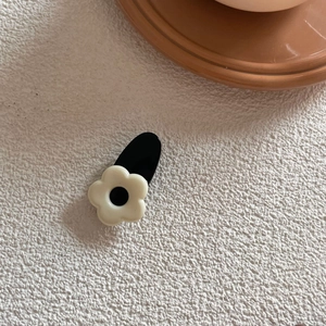 Detailed macro view of a cute black and white flower hair clip with a resin finish