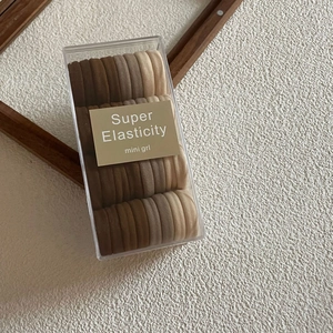 Macro detail of earth-toned high elasticity hair ties in a clear rectangular storage box