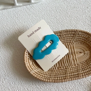 Detail of a bright blue wave-shaped acrylic hair clip on handmade accessory card