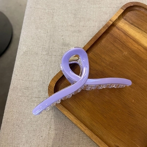 Detail of lavender ice glaze hair claw clip showing metal spring on a wooden tray
