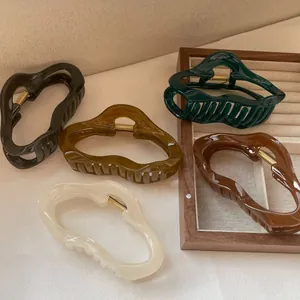 Détail de pinces à cheveux ondulées aux tons terre sur un plateau à bijoux en bois