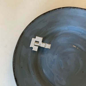 Silver geometric metal hairpin with inlaid zircons on a blue ceramic display tray