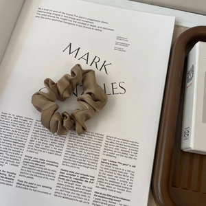 Detailed texture of mocha brown satin scrunchie with soft pleated cloud design fabric