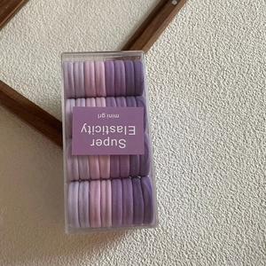 Detailed view of 24 purple gradient high elasticity hair bands in a clear storage box