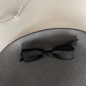 Barrette à cheveux nœud noir élégante sur assiette en céramique avec perles