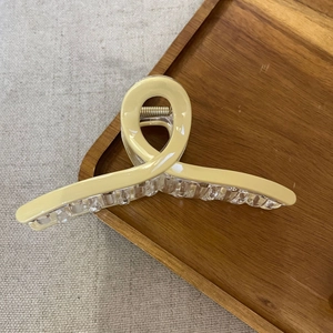 Elegant cream yellow cross hair claw clip for women on a rustic wooden tray setup