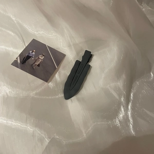 Black matte wavy hair clip on white silk fabric background for women's hair styling