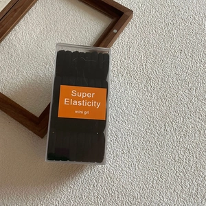 Detail of high elasticity black hair ties neatly stacked in a transparent storage box